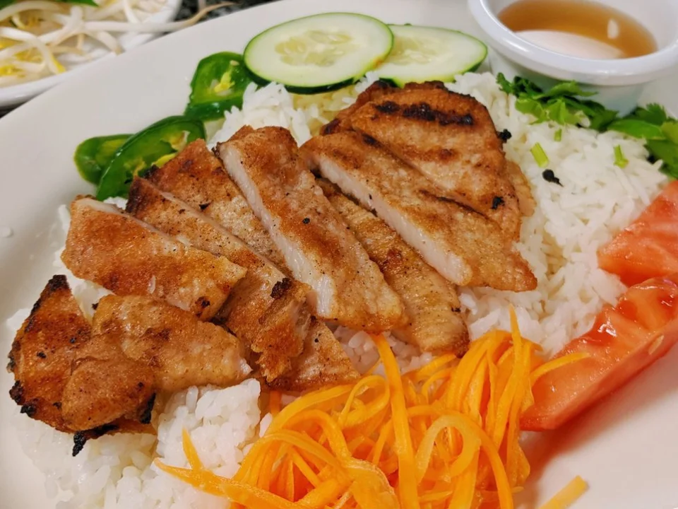 Grilled BBQ Pork Chop with Rice - Juicy, marinated pork chop grilled to perfection and served over steamed rice with pickled vegetables and a side of fish sauce. A hearty Vietnamese favorite.