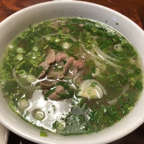 Pho Tai (Rare Beef Noodle Soup) - Our signature pho features a rich, slow-simmered beef broth with tender rare beef slices, rice noodles, and fresh herbs. A comforting classic that keeps guests coming back.